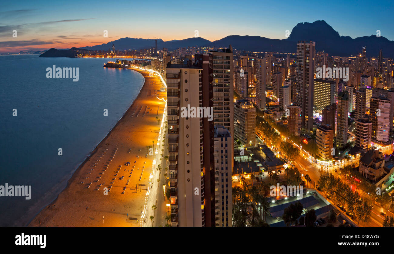 Benidorm`s Levante beach, panoramic from north end corner  at dusk, with its promenade, front hotels and apartments lighted. Stock Photo